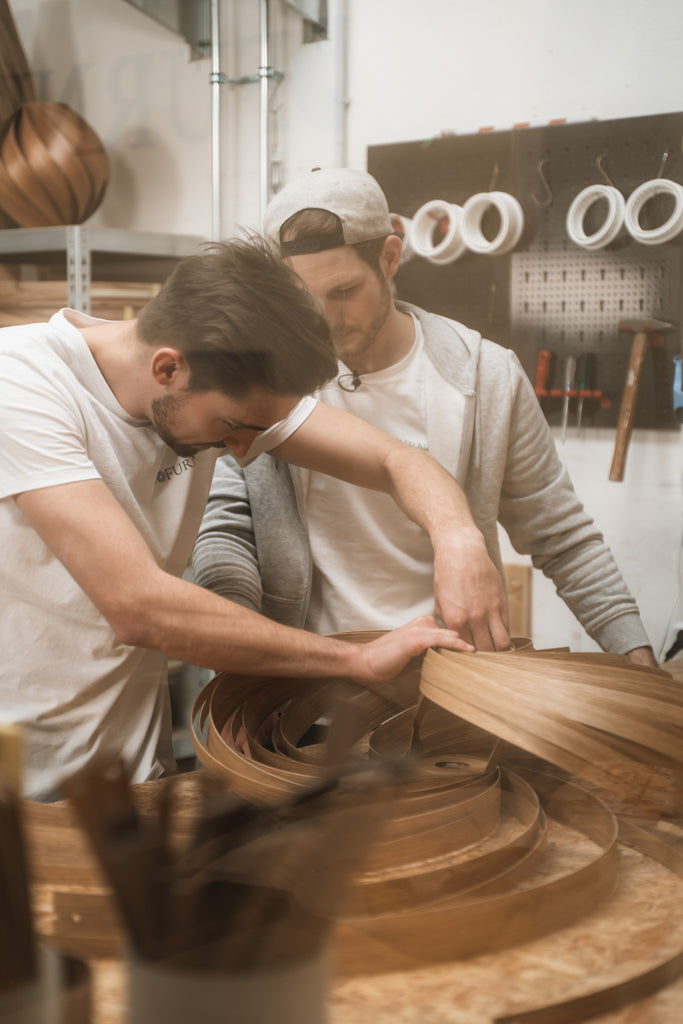 Founder Manuel Döpper with Alex during the production of a solid wood pendant lamp from the collection Veneria, teamwork is required